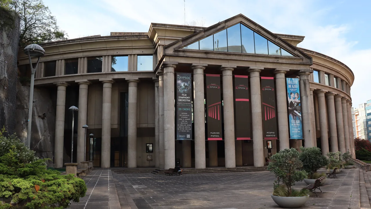 La columnata curva del Palacio de la Ópera de A Coruña, con los carteles de la temporada colgados entre las columnas.