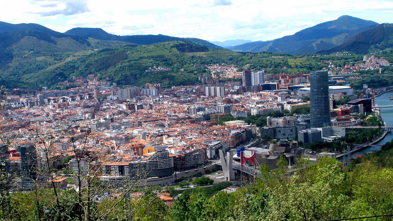 Bilbao entero visto desde el mirador de Artxanda: los tejados, la ría y la torre Iberdrola entre montes verdes.