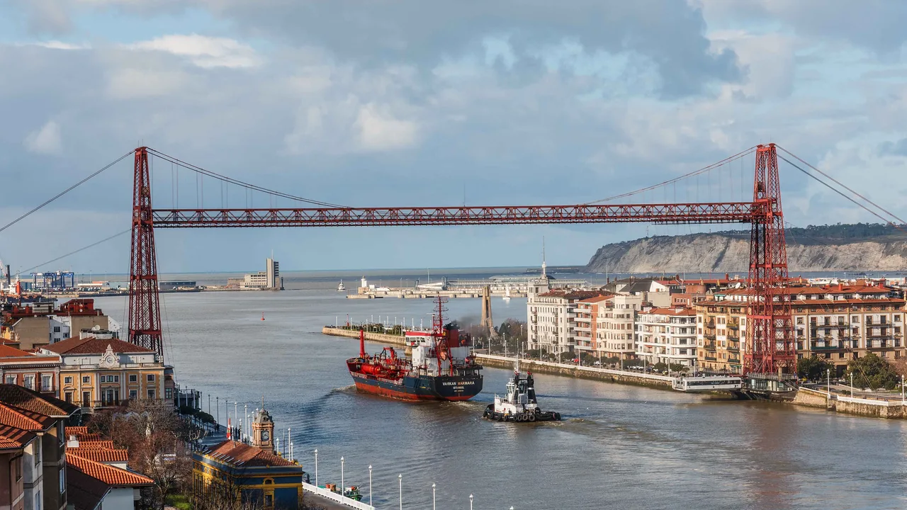 El Puente Bizkaia sobre la ría, con la barquilla suspendida del tablero y Portugalete y el mar al fondo.