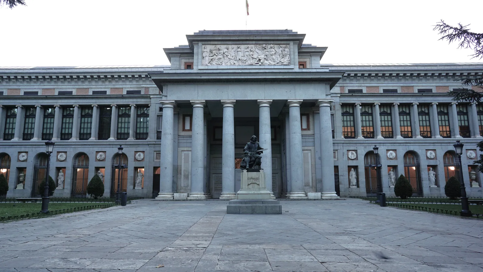 Puerta de Velázquez del Museo del Prado de frente, con la estatua de Velázquez entre las columnas.
