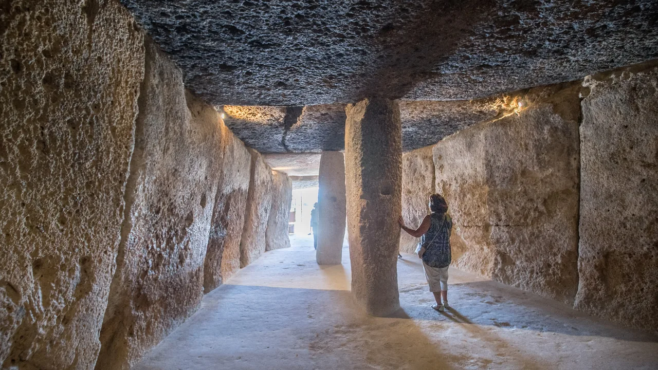 El corredor de piedra del dolmen de Menga, con una mujer sola junto a uno de los pilares monolíticos.