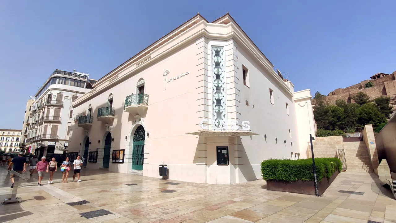 La fachada blanca del Cine Albéniz con su rótulo de cines y la ladera de la Alcazaba detrás.