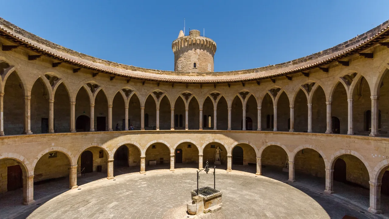 El patio circular del Castell de Bellver, con sus dos pisos de arcos en piedra dorada y la torre del homenaje al fondo.