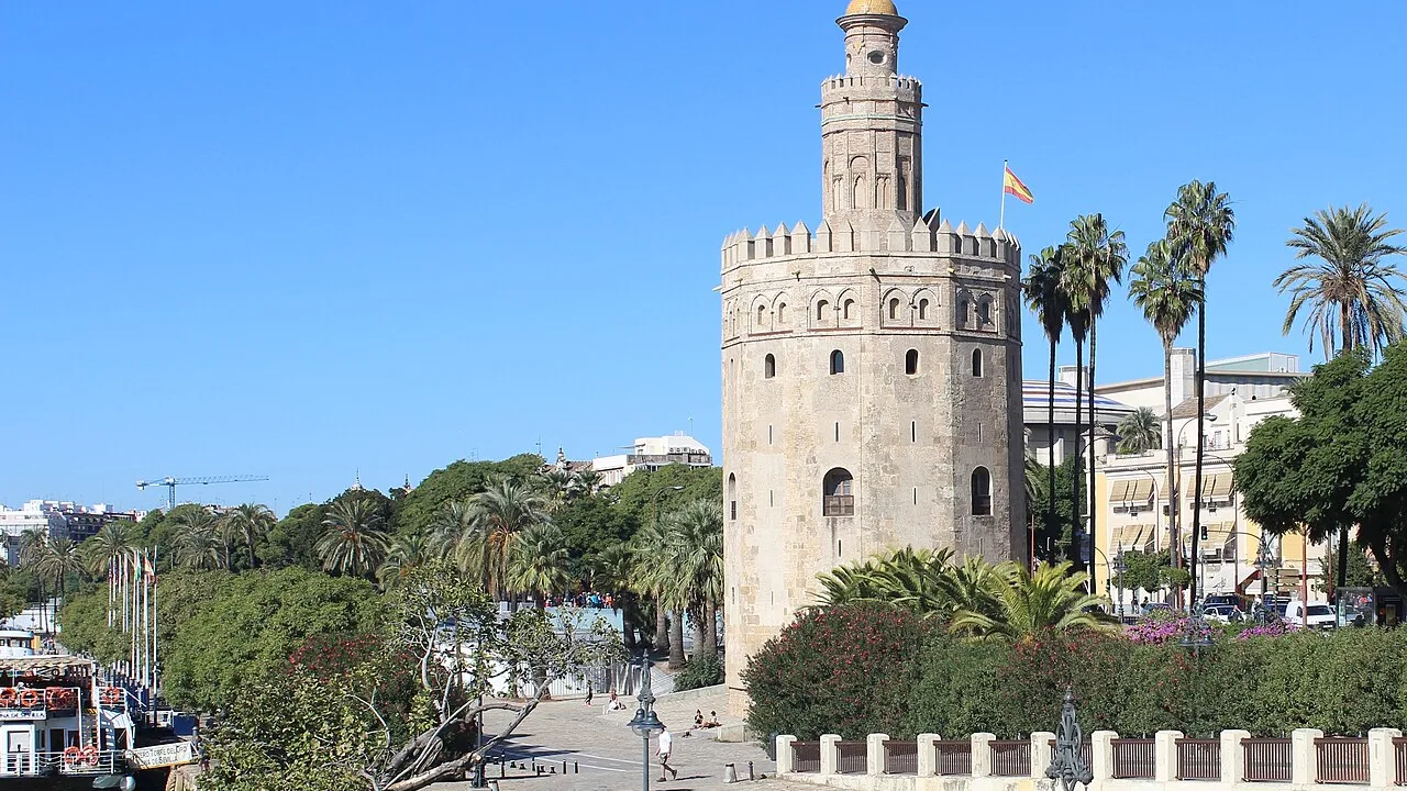 La Torre del Oro a orillas del Guadalquivir, con el río y el paseo de los muelles de Sevilla.