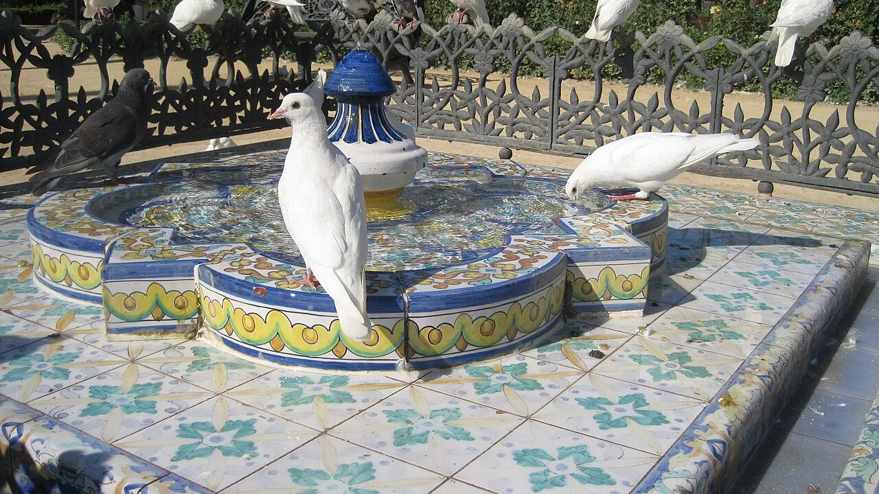 Una glorieta con azulejos y bancos a la sombra de los árboles del Parque de María Luisa de Sevilla.