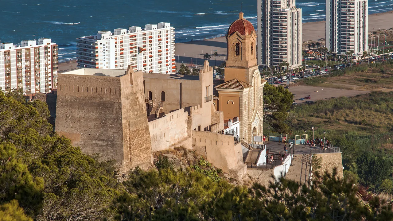El castillo y el campanario de Cullera sobre el cerro, con el pueblo y el mar Mediterráneo al fondo.