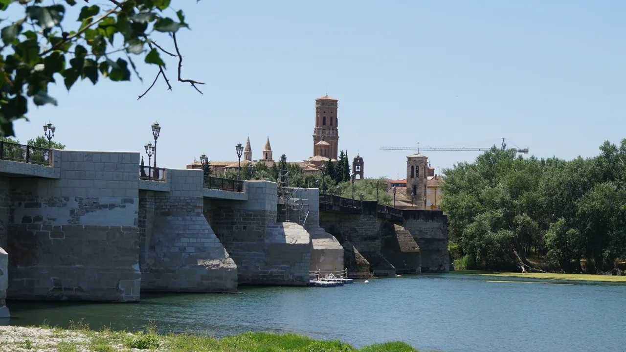 El puente de piedra sobre el Ebro en Tudela, con la torre de la catedral y los campanarios del casco al fondo.